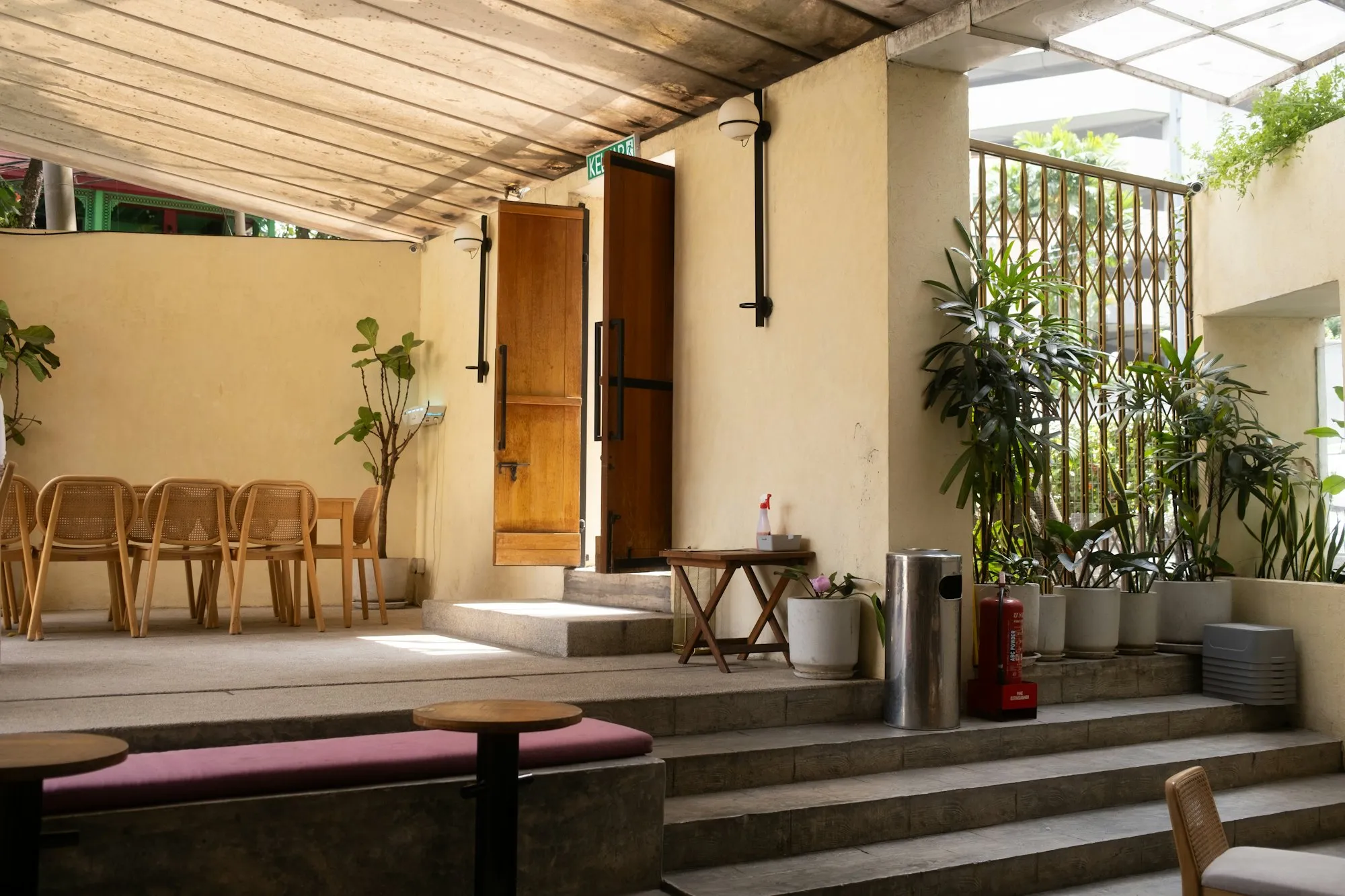 Sunlit courtyard terrace with timber doors and plants