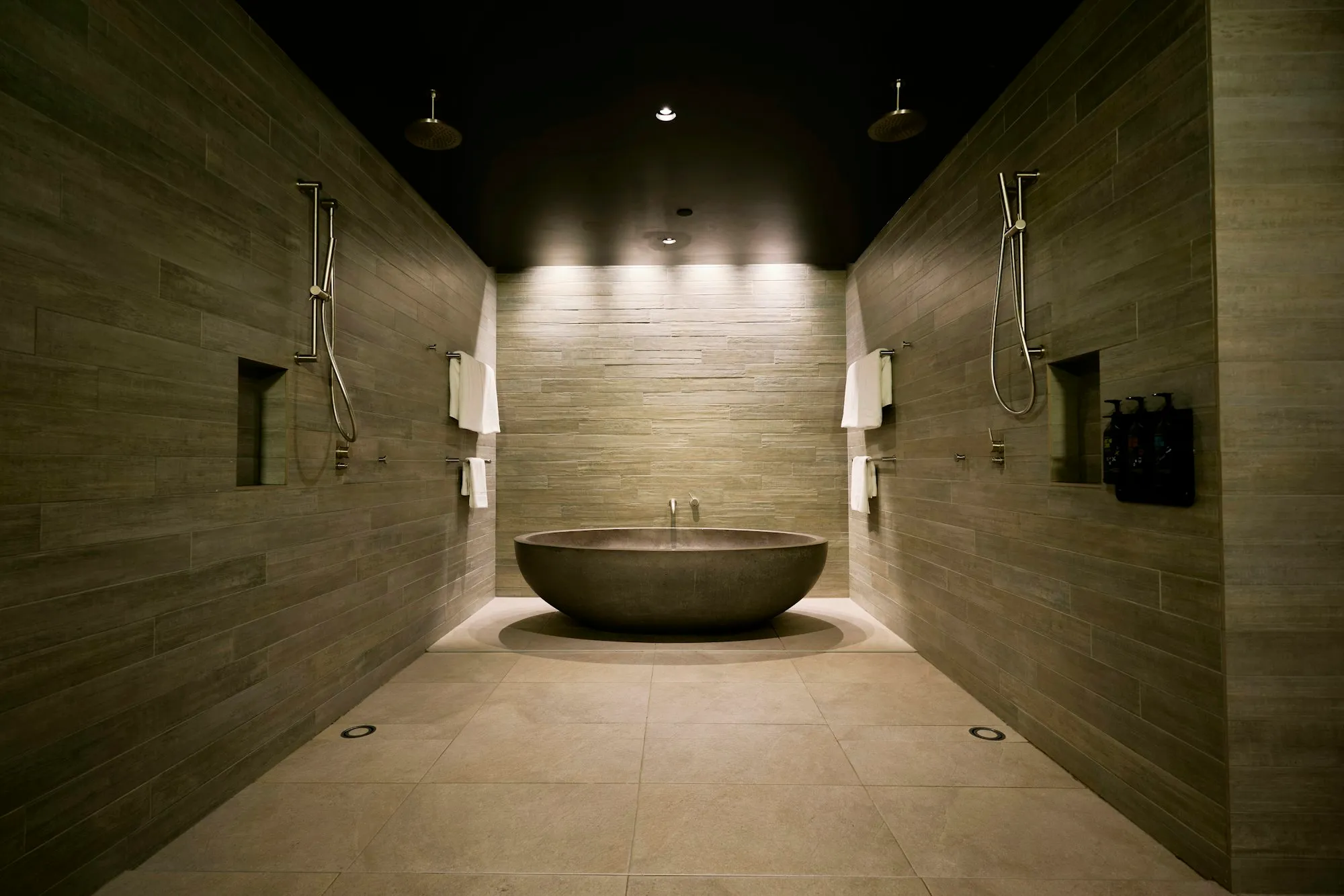Stone bathtub in a dark tiled bathroom