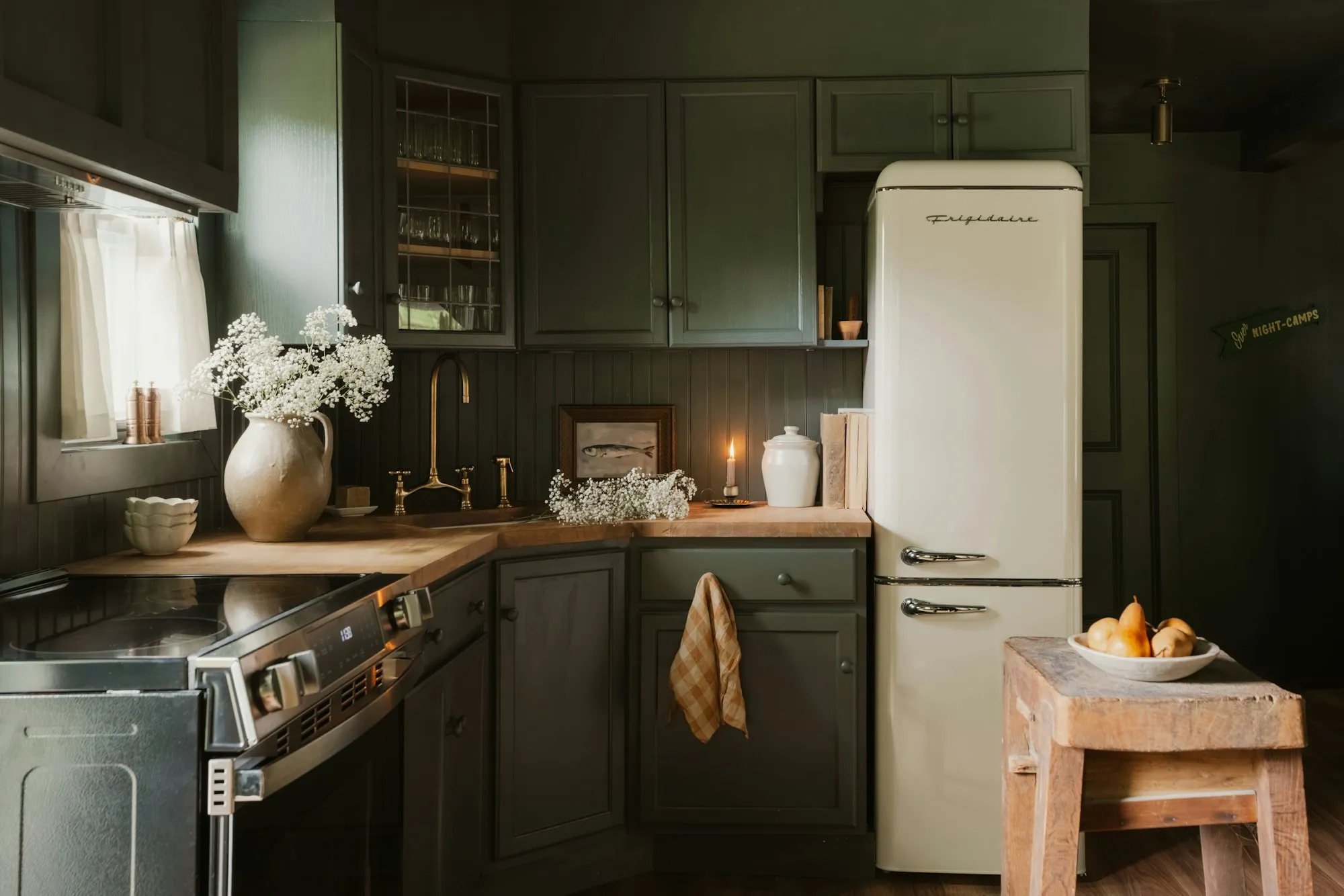 Deep green kitchen with brass details and warm light